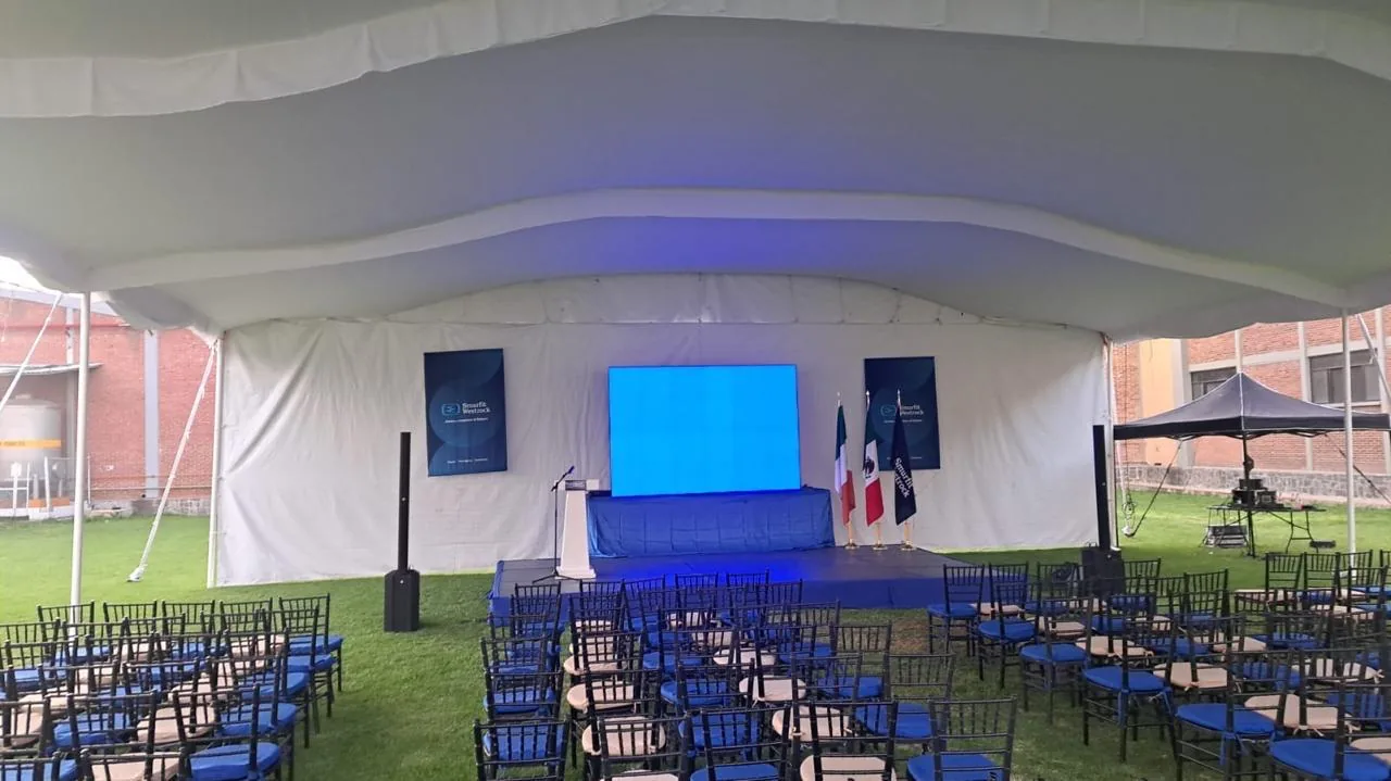 Filas de sillas y escenario bajo una carpa